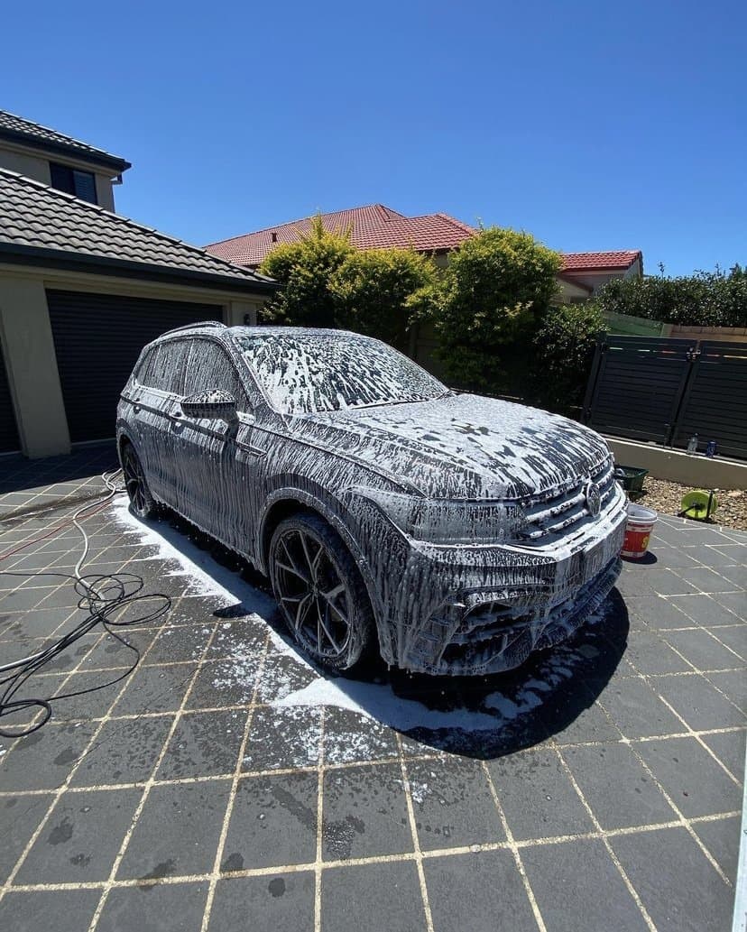SUV covered in snow foam during a maintenance wash