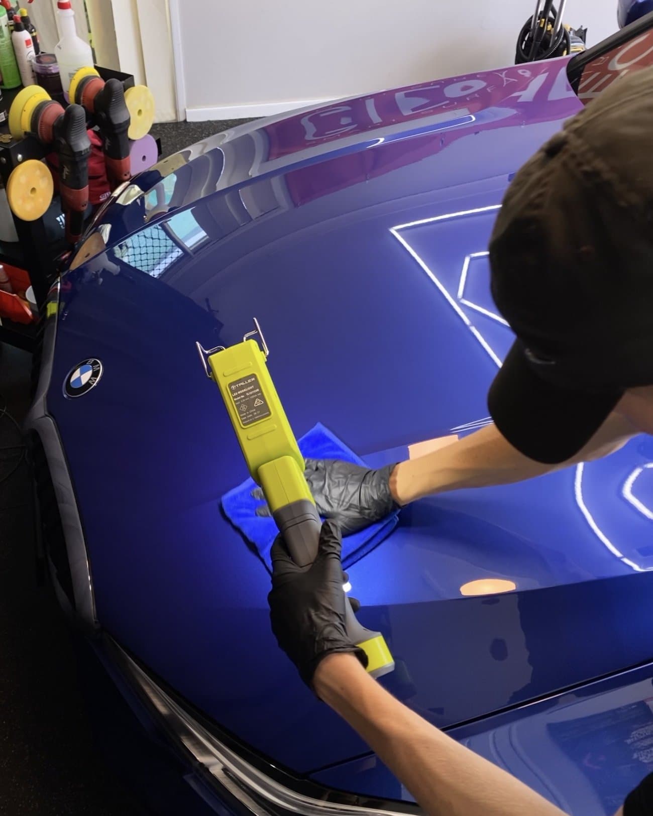 Technician inspecting paint finish under an LED swirl-finder light